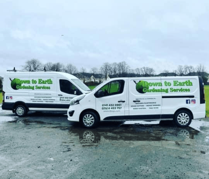 image of two vans facing each other in the rain and concrete with the Down to Earth Garden Services logos and advertising in green on the vans.