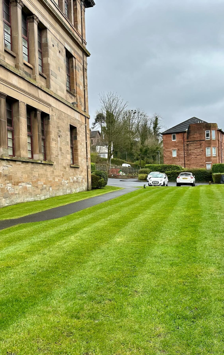 Lovely striped mowed grass on a large grassy area behind an victorian style glasgow tenement building