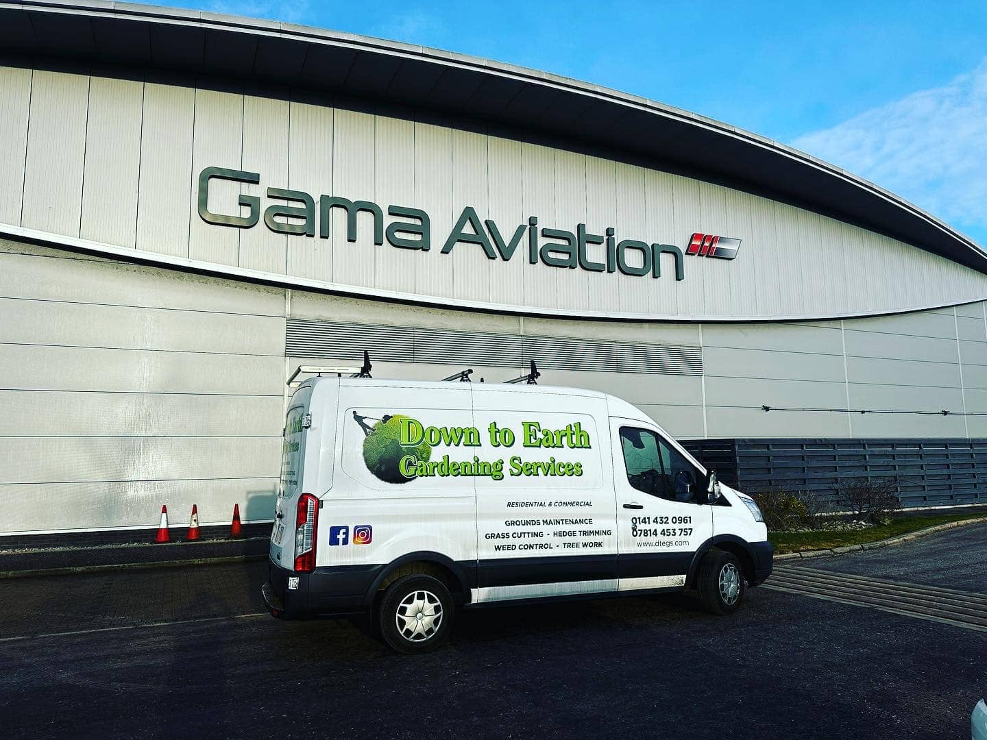 image of two vans facing each other in the rain and concrete with the Down to Earth Garden Services logos and advertising in green on the vans.
