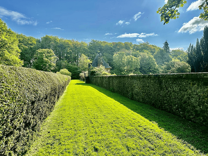  A beautiful stately home front garden with superbly mowed grass and pebble stones around the large front parking area with a 4 by 4 vehicle parked at the corner 